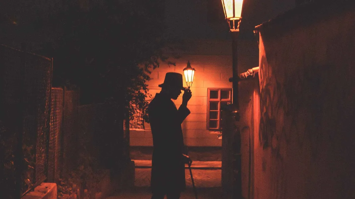 Costumed guide telling legends on a Prague ghost tour near Old Town Square at night, Czechia